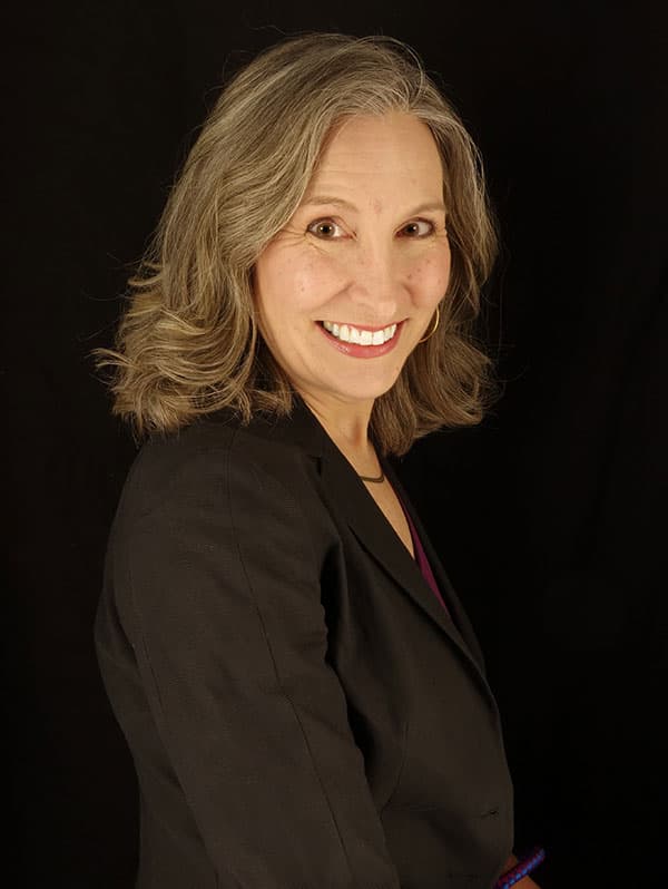 Portrait of Beth Allgood smiling in black suit